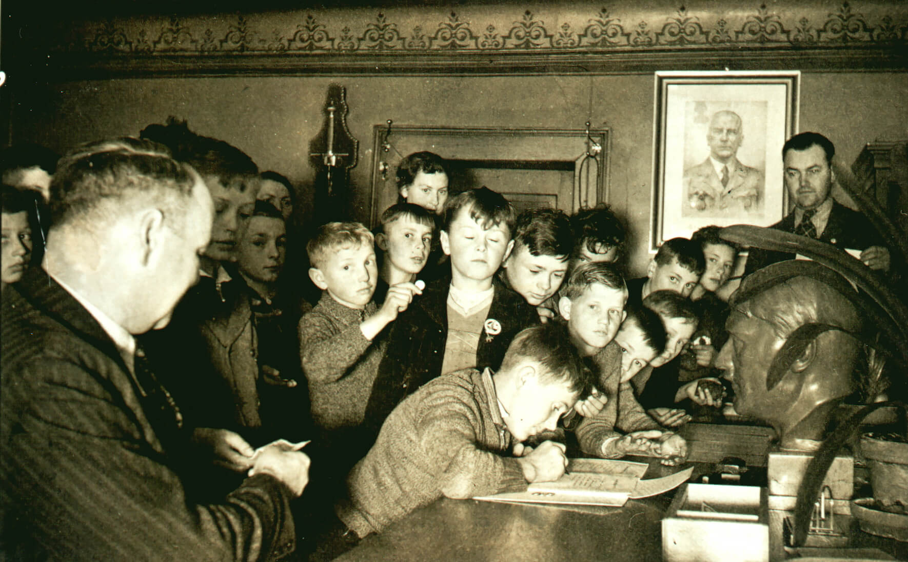 Bräunlinger Kinder beim Einschreiben in das Metall-Spendenbuch „im Angesicht des Führers“ (vor der Hitlerbüste) in einem Zimmer des Rathauses Bräunlingen im Nationalsozialismus 1940. - Geschichtswerkstatt Bräunlingen